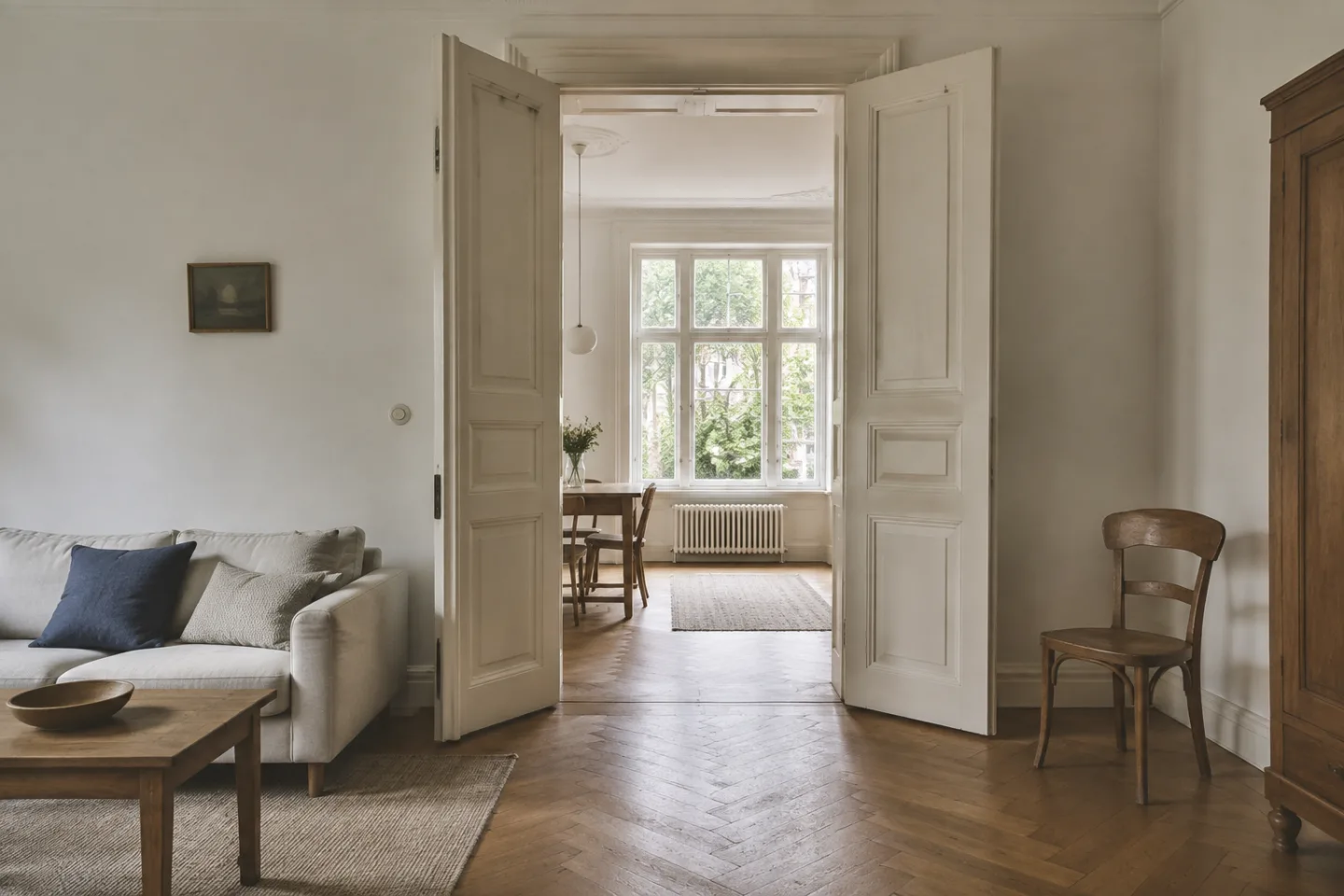 Altbauwohnung mit Flügeltüren, Parkett und einem hellen angrenzenden Zimmer.